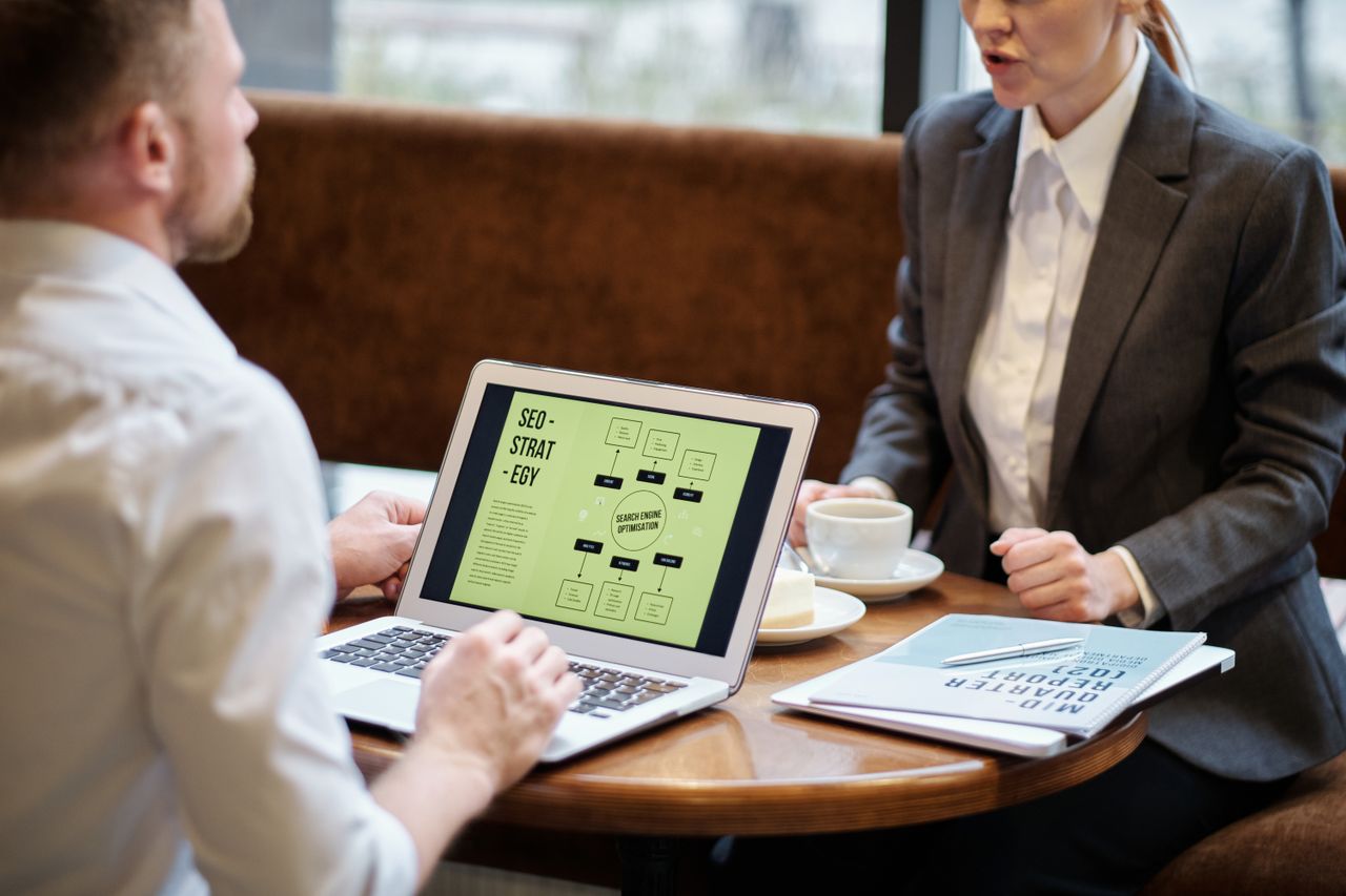 A man and woman holding a business meeting in a cozy cafe, discussing SEO strategy.